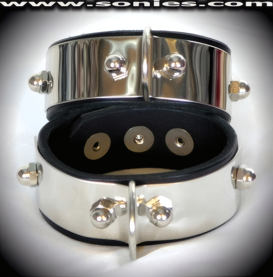 Pair of Sajama Stainless Steel with leather wristbands with large metal D-ring for your endless imagination. This quality piece is crafted from genuine leather and features bold stainless steel front plate with metal acorn nuts and adjustable metal snaps closure. Rounded edge for comfort and durability. It pairs magnificently with any number of leather ankle restraints or arm binders. This style is perfect for stage, life style events, pride week, monthly play parties, fetish events and adult alternative lifestyle gatherings.   Style: LC-26